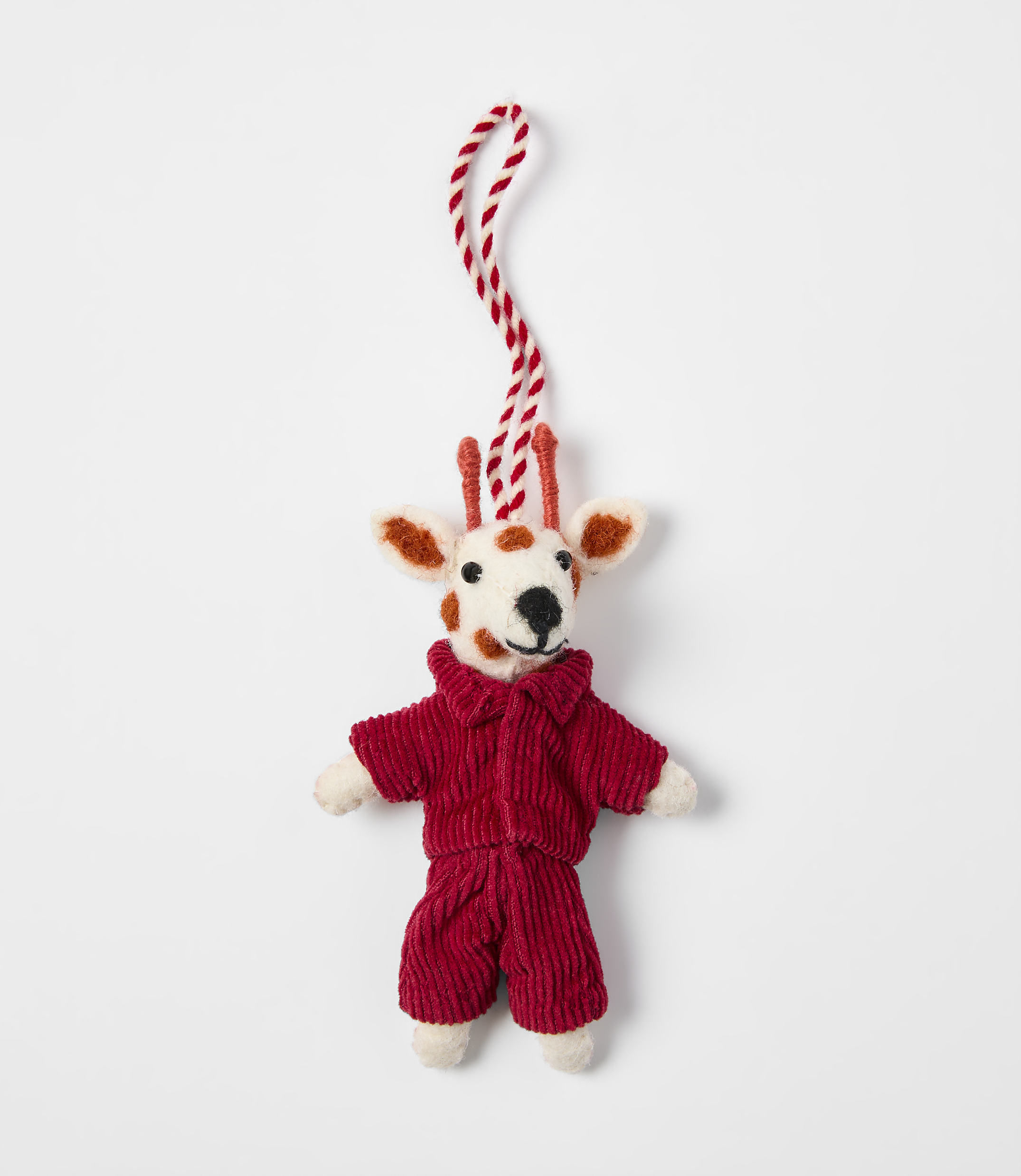 A small felted deer ornament wearing a red corduroy outfit hangs from a red and white string against a plain white background.