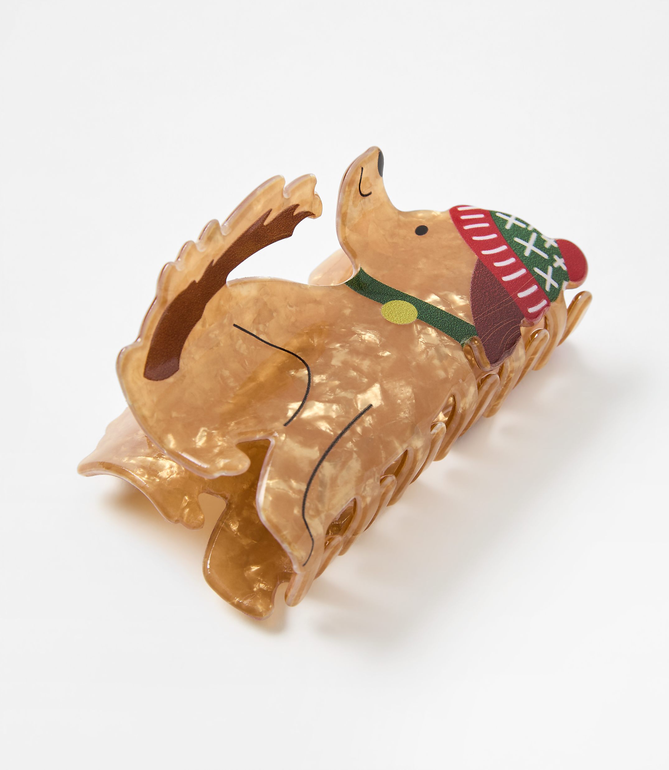 A dog-shaped hair claw clip wearing a festive red and green hat sits on a plain white background.