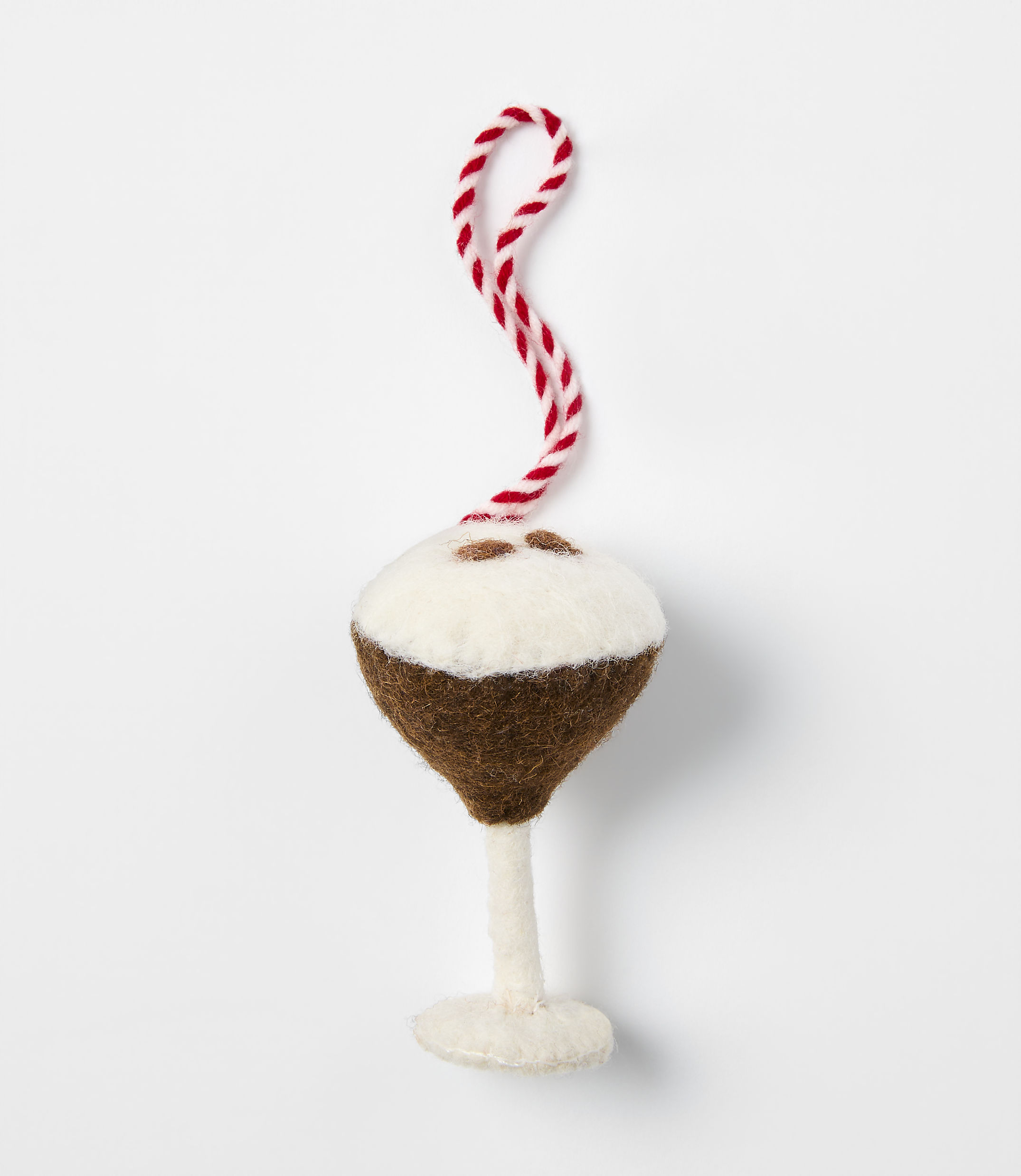 A felt ornament shaped like a cocktail glass with a brown drink and white foam sits against a plain white background.