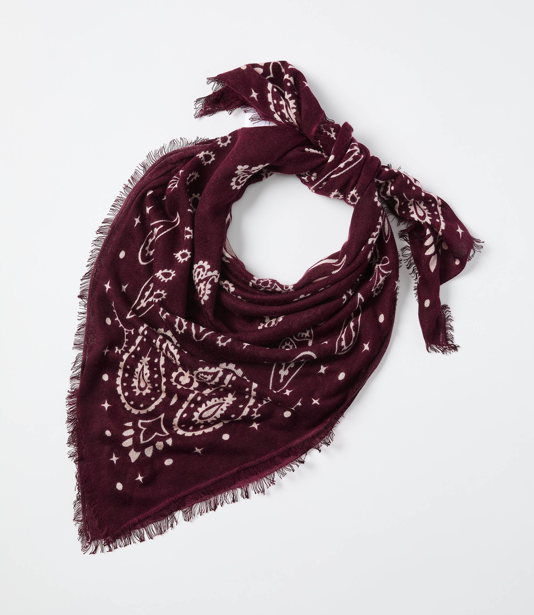 A maroon paisley-patterned bandana with frayed edges is tied in a knot against a plain white background.