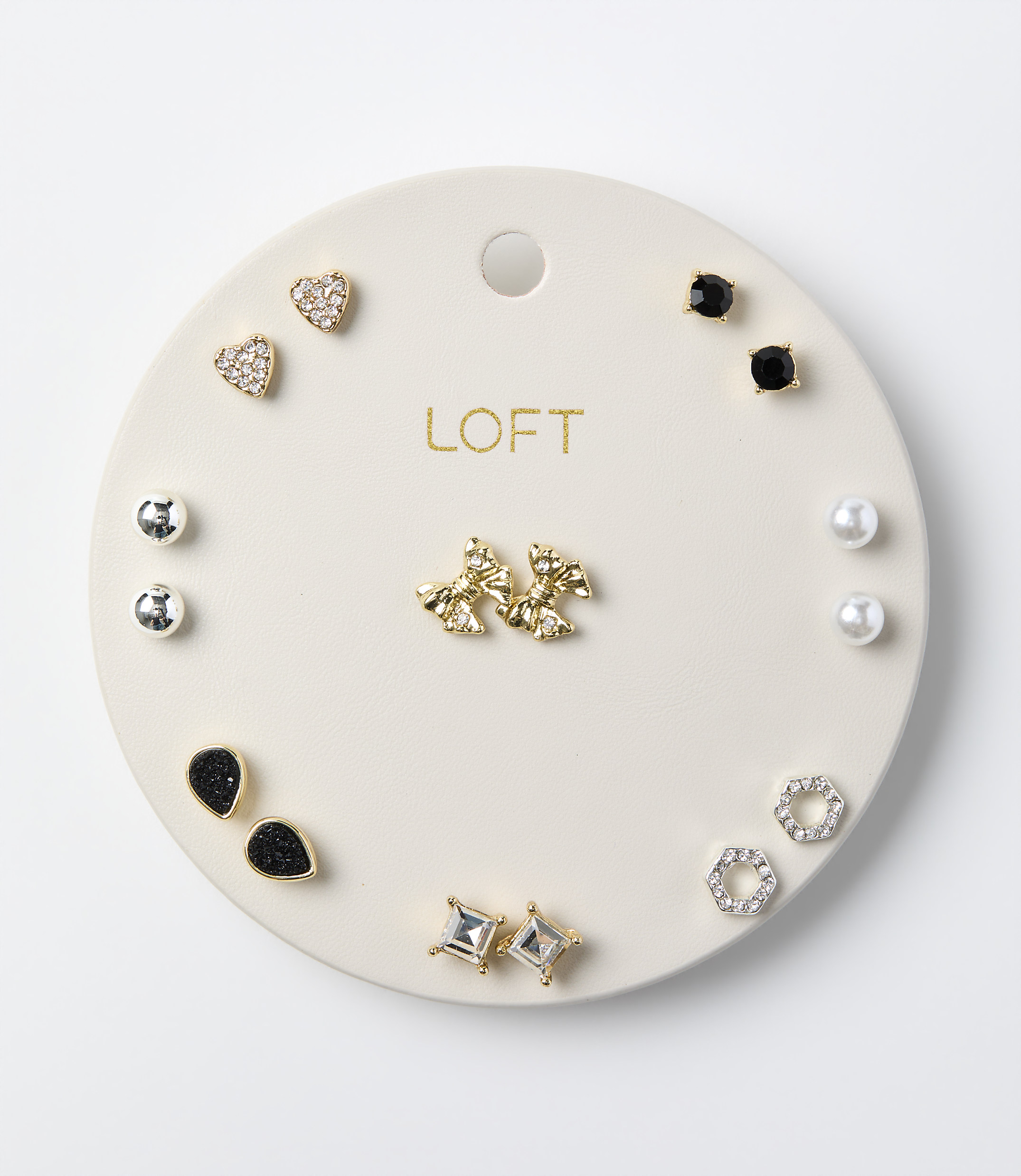 Various pairs of stud earrings are arranged on a circular white LOFT display card against a plain white background.
