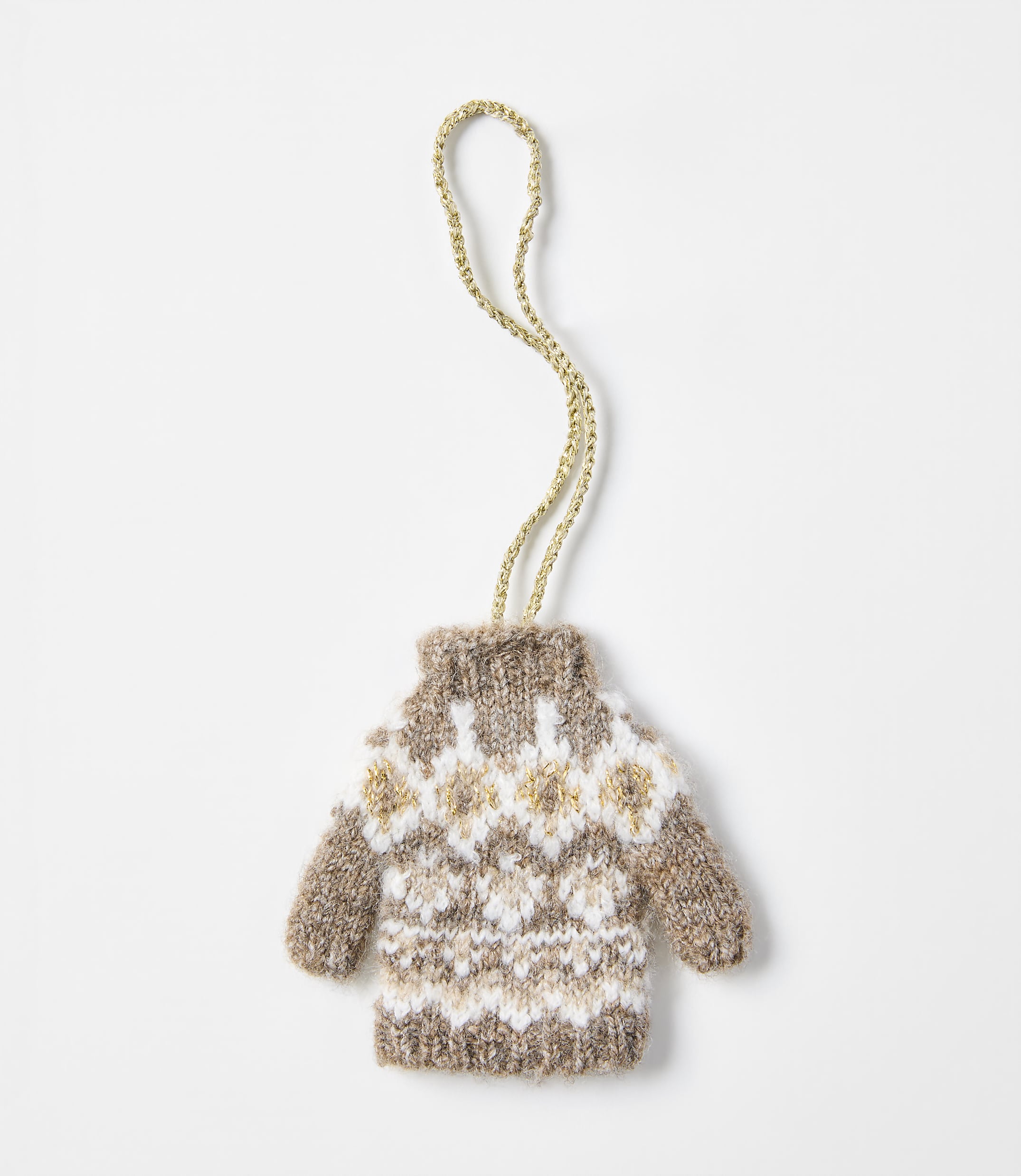 A small, knitted brown and white patterned sweater ornament with a gold string hangs against a plain white background.