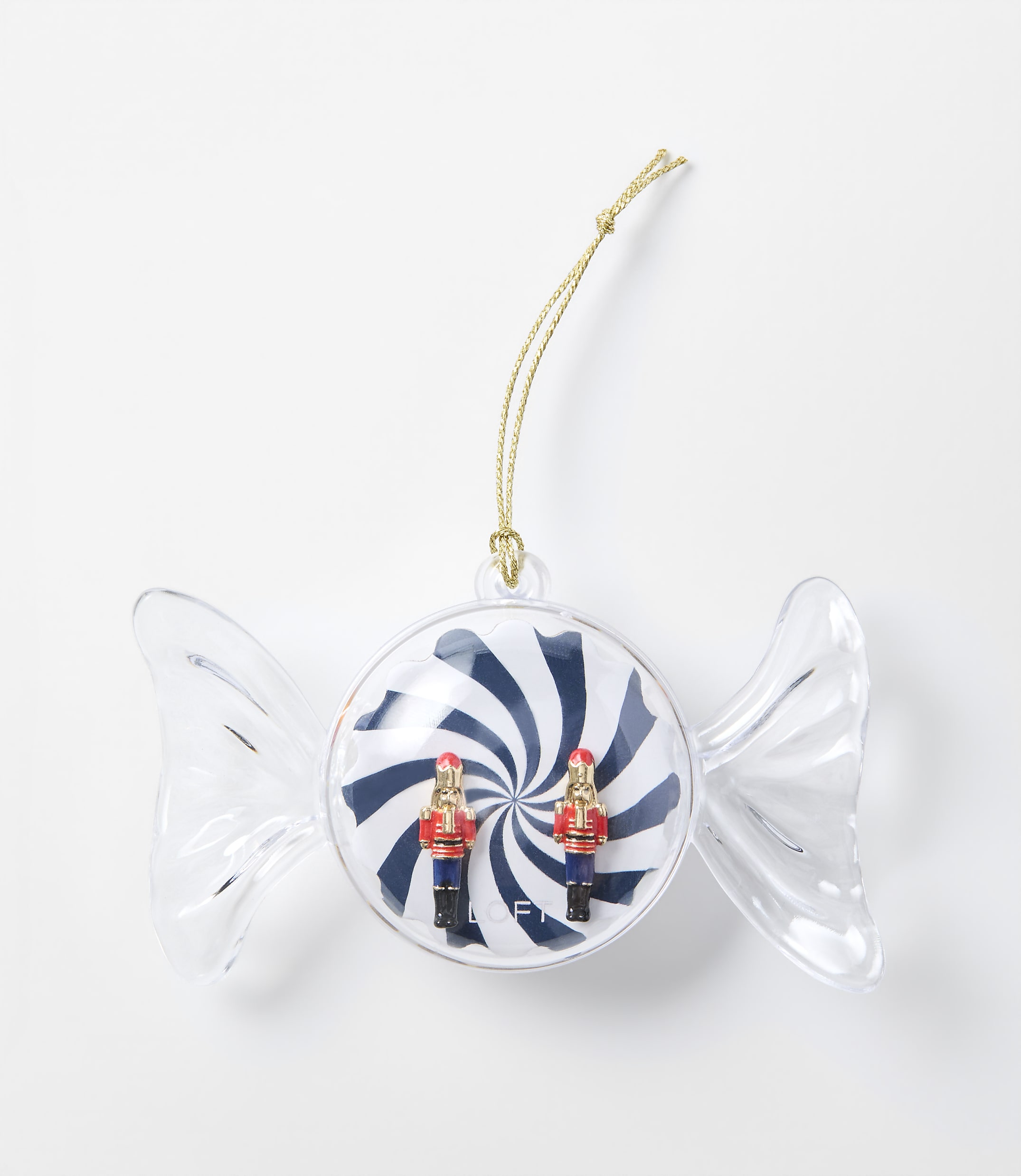 A clear candy-shaped ornament containing two small nutcracker figures against a blue and white swirl background, set against a plain white surface.