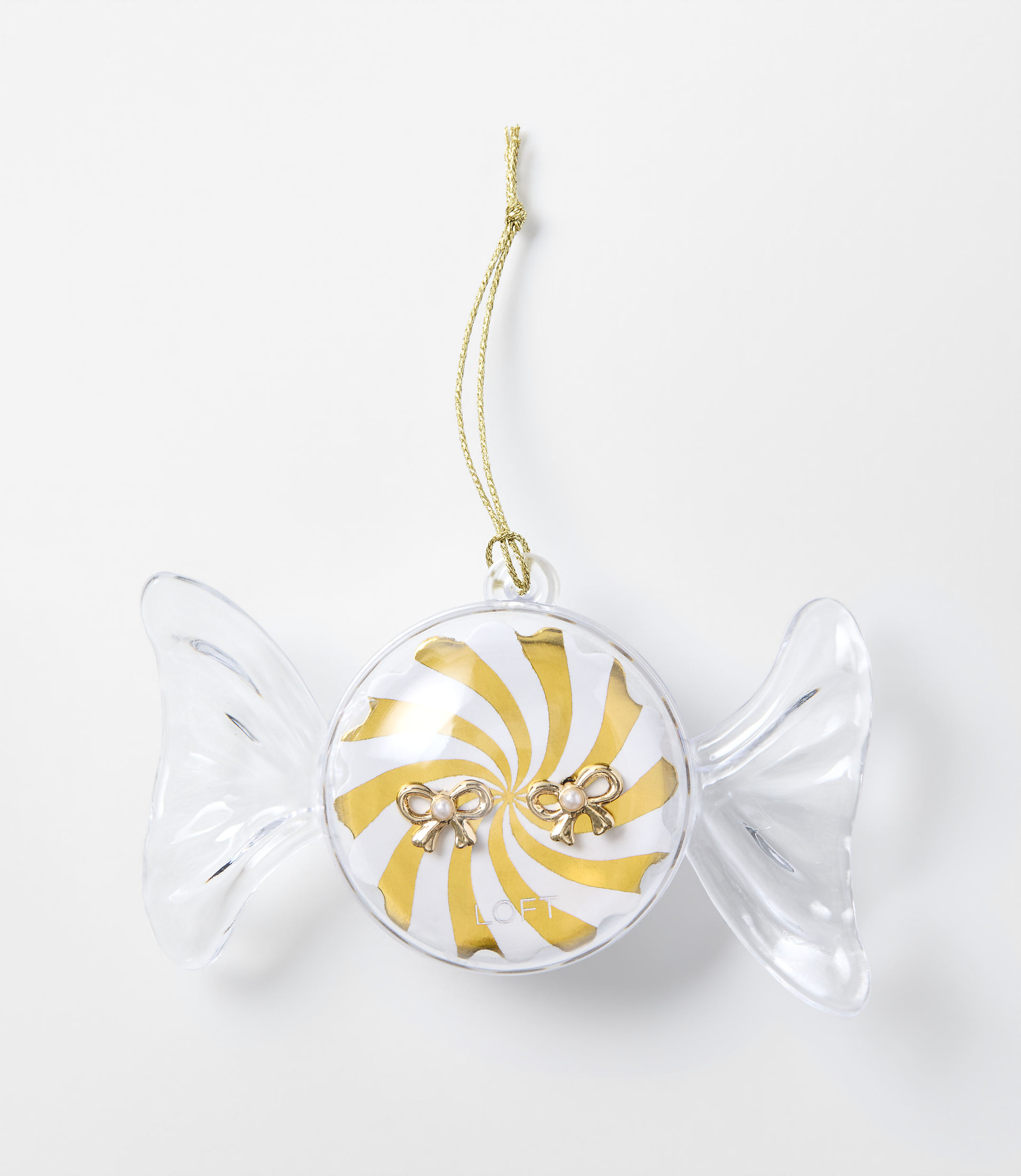 A clear, candy-shaped ornament with a gold and white swirl center and small bows sits against a plain white background.