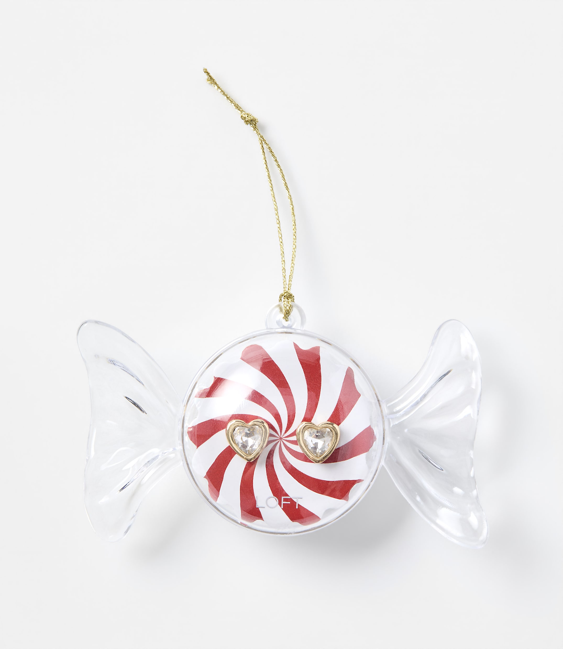 A clear candy-shaped ornament with a red and white peppermint center and two heart-shaped gems sits against a plain white background.