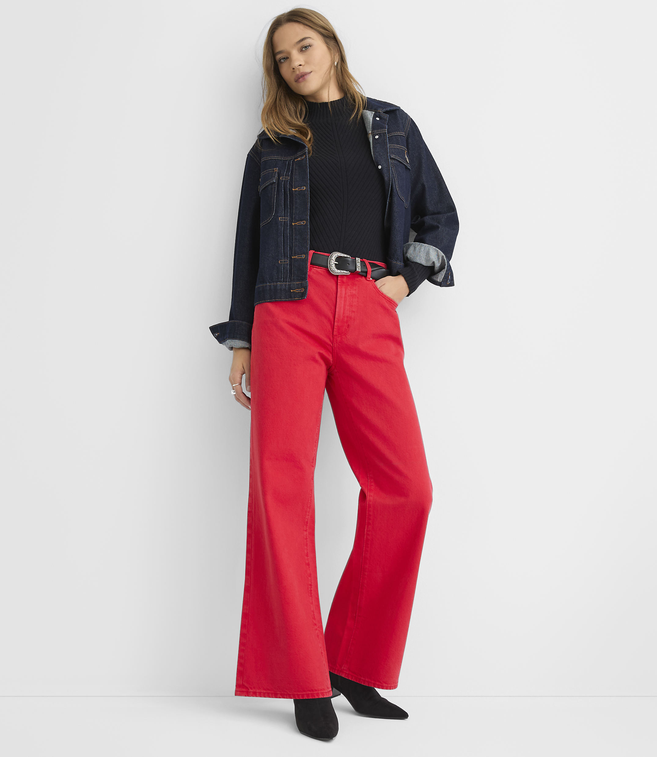 A woman in a red denim jacket and wide-leg pants stands against a plain white background.