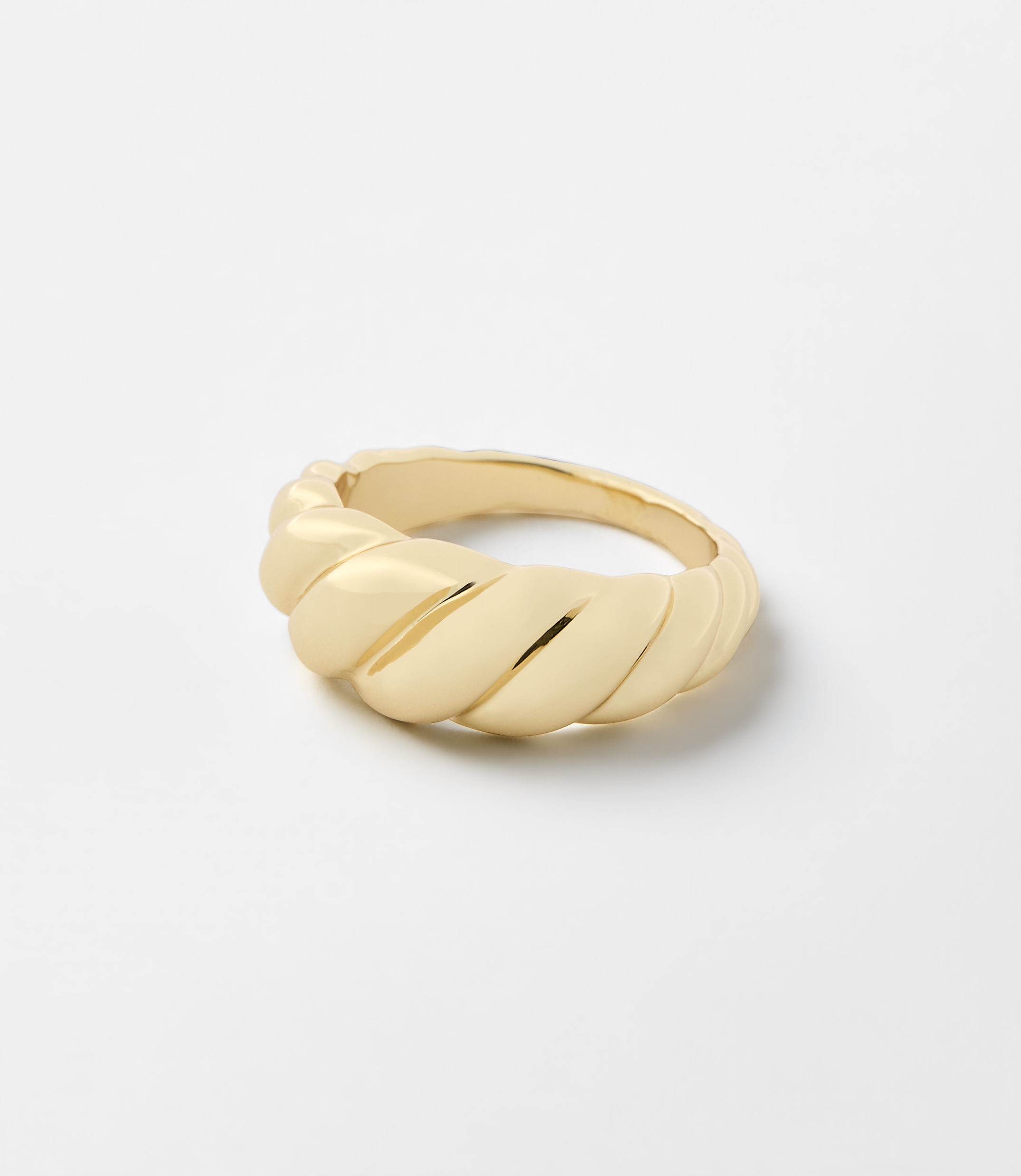 A gold twisted ring sits centered on a plain, light gray background.