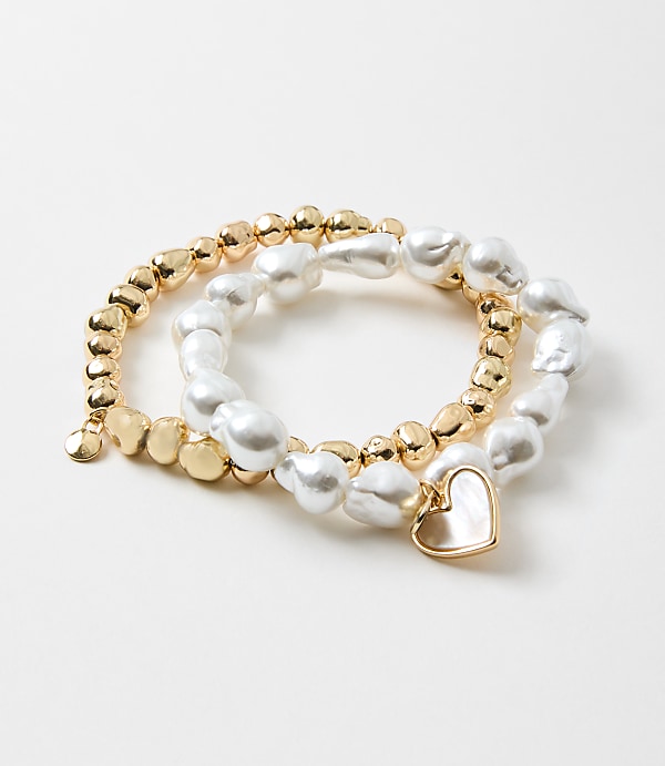 The image shows a set of three bracelets made of gold-colored beads and white irregular-shaped pearls, with a small heart-shaped charm attached to one of the bracelets.