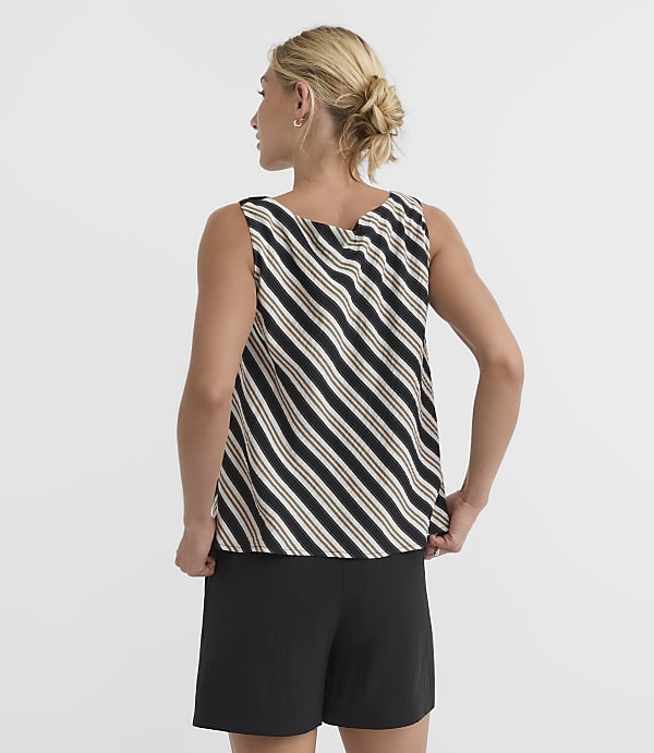 A woman in a striped tank top and black shorts stands against a plain white background.