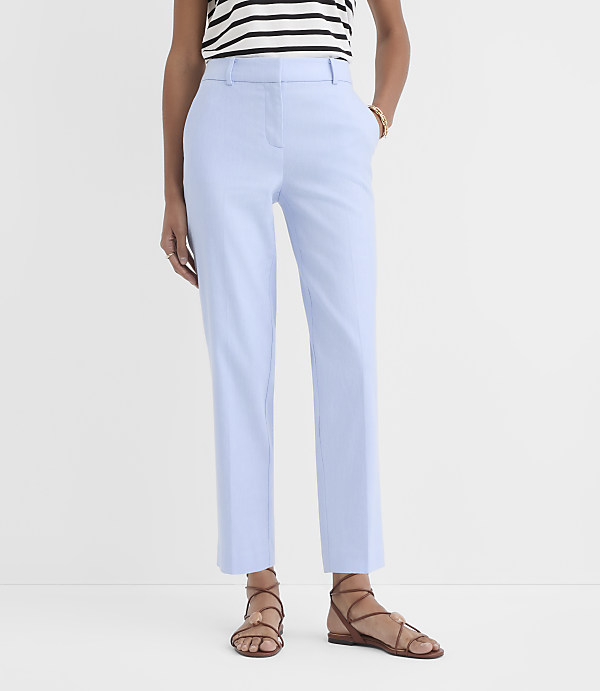 A person wearing light blue pants and sandals stands against a plain white background.