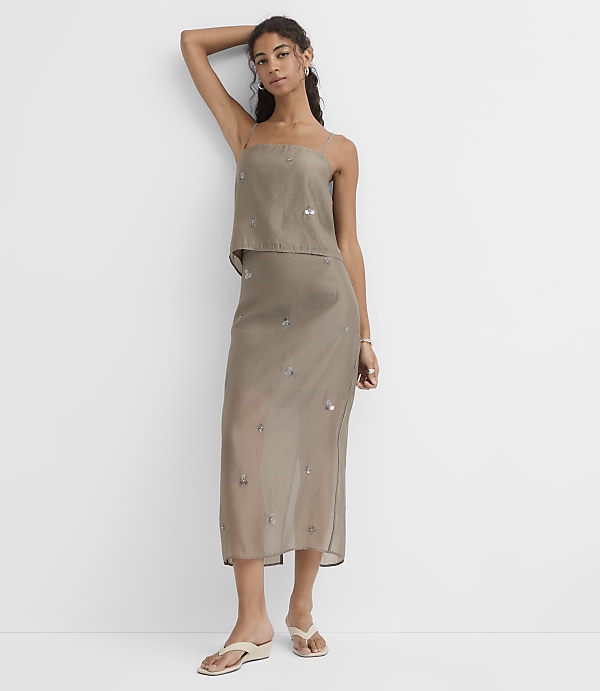 A woman in a strapless, sequined dress stands against a plain white background.