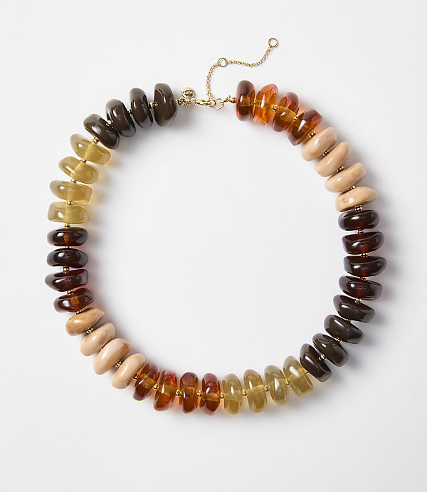A colorful beaded necklace with amber, wood, and dark brown beads is laid out on a plain white background.