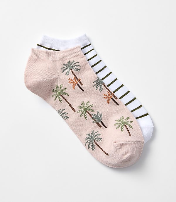 A pair of ankle socks, one with a pink background and palm tree pattern, the other with white and green stripes, are laid out on a plain white background.