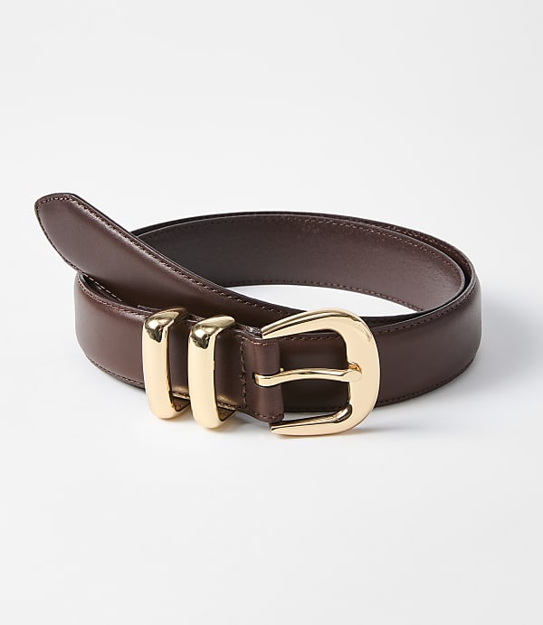 A brown leather belt with a gold buckle and three gold loops rests on a white background.