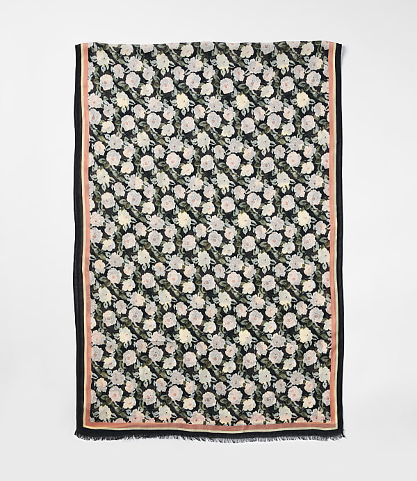 A floral scarf with a black background and pink border is laid out against a plain white background.