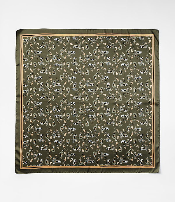 A square silk scarf with a repeating paisley pattern in shades of green, cream, and peach is laid flat against a plain white background.