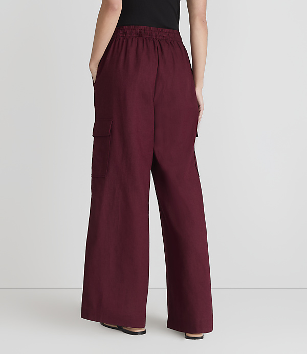 A person stands with their back to the camera, wearing maroon cargo pants and black shoes, against a plain white background.