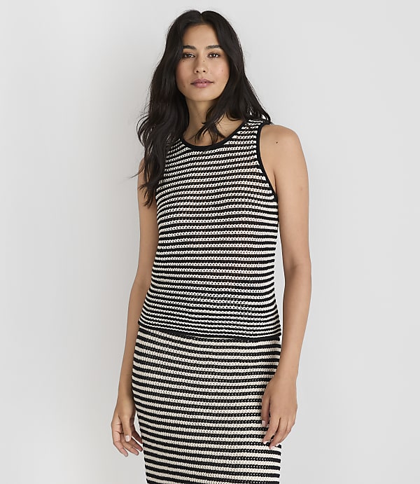 A woman in a striped top and skirt stands against a plain white background.