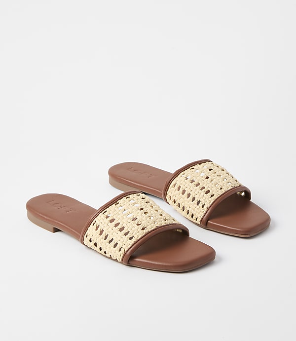 A pair of brown slide sandals with woven straw straps rest on a plain white background.