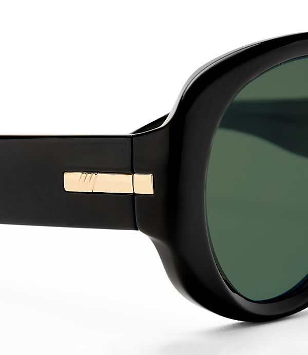 A close-up of black sunglasses with gold accents is set against a plain white background.