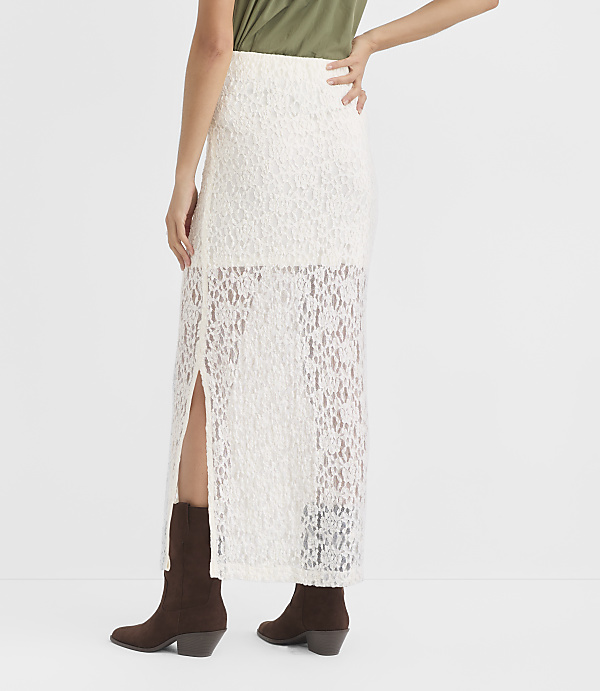 A person in a white lace skirt and brown boots stands against a plain white background.
