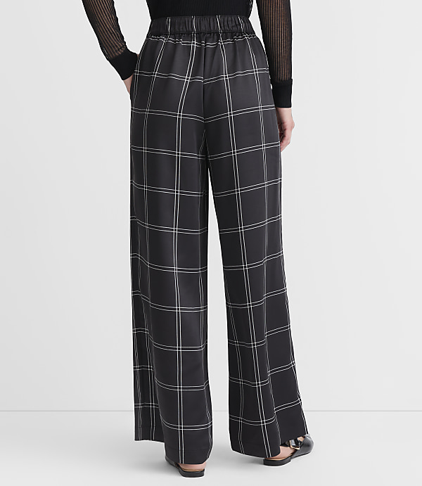 A person wearing wide-leg plaid pants stands against a plain white background.