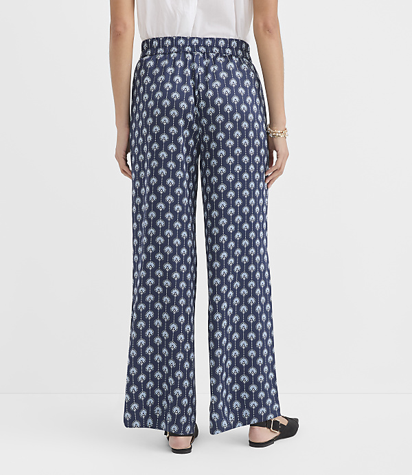 A person wearing patterned wide-leg pants stands against a plain white background.
