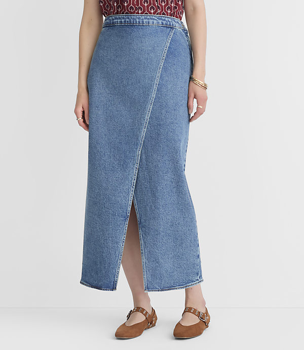 A person stands in a light blue denim wrap skirt with a slit, wearing brown Mary Jane shoes against a plain white background.