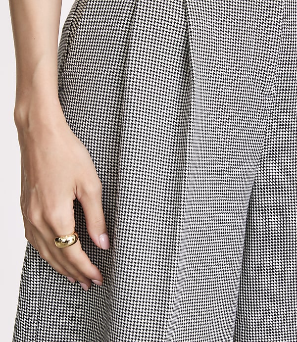 A hand with a gold ring rests on patterned fabric in the foreground, with more of the same fabric filling the background.