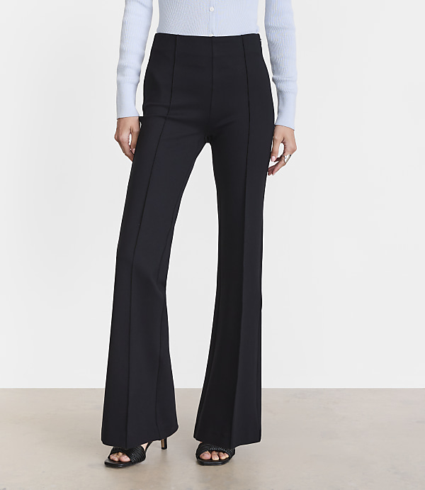 A person wearing black flared pants and a light blue shirt stands against a plain white background.