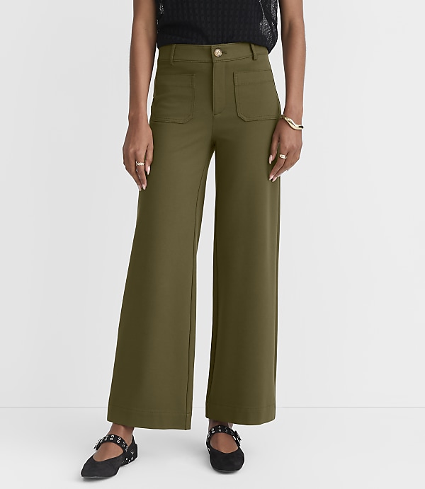 A person models olive green wide-leg pants with a black top and black flats against a white background.
