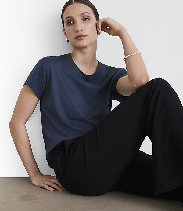 A woman in a navy t-shirt and black pants poses against a plain white background.