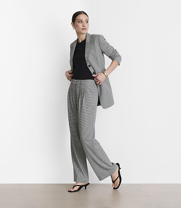 A woman in a black and white checkered suit stands against a plain white background.