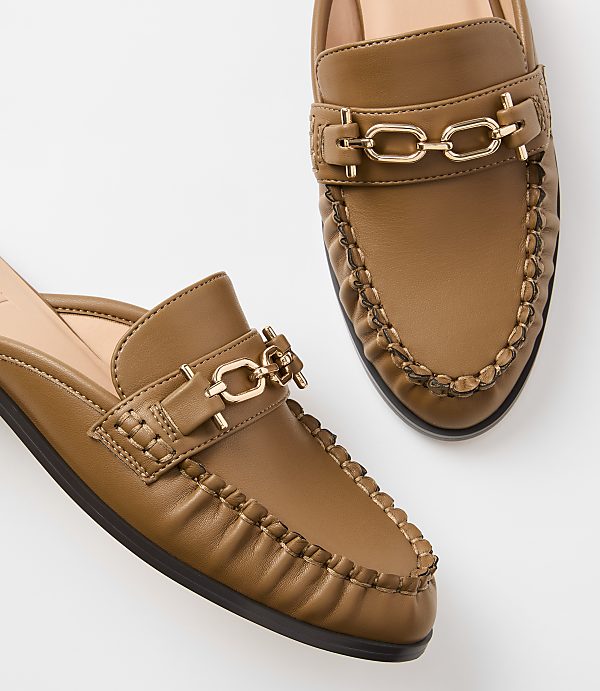Two brown leather mules with gold chain accents are displayed against a plain white background.