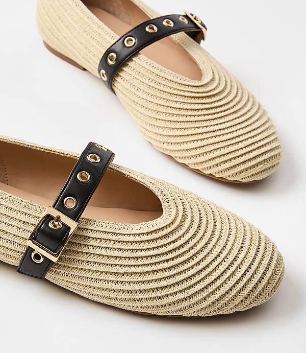 Two straw Mary Jane flats with black buckle straps are displayed against a white background.