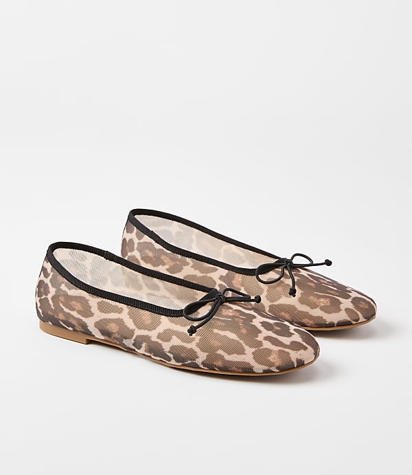 A pair of leopard-print ballet flats with black trim and bows rests on a plain white background.