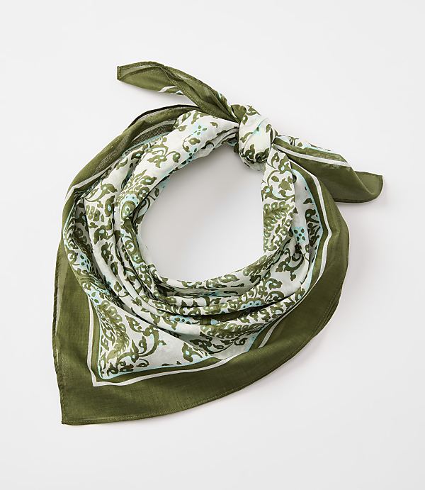 A green bandana with a white and green paisley pattern is tied in a knot against a plain white background.