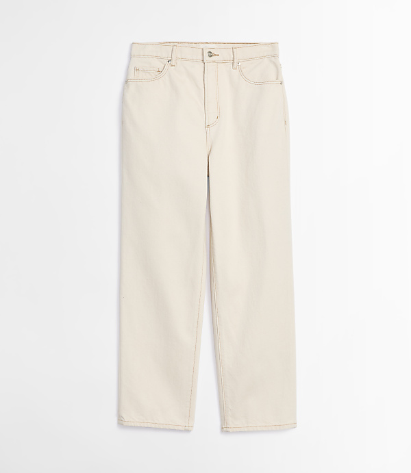 A pair of cream-colored jeans with visible stitching lies flat against a plain white background.