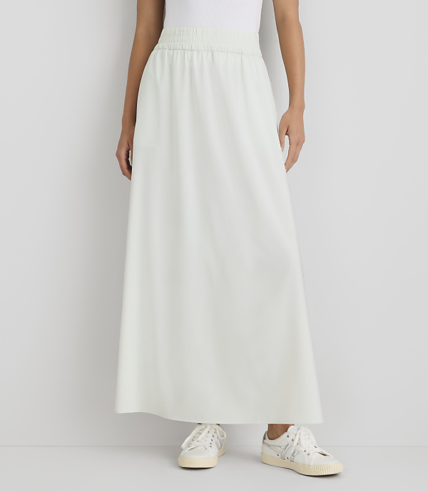 A person stands in a light green maxi skirt and white sneakers against a plain white background.