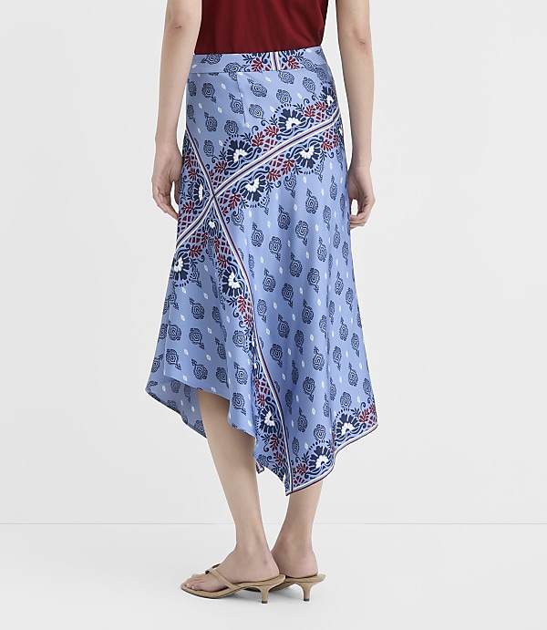 A woman in a blue patterned skirt stands against a plain white background.