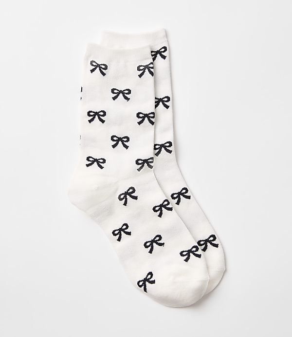 A pair of white socks with a pattern of black bows are displayed against a plain white background.