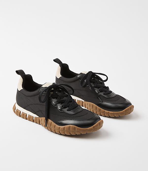 A pair of black sneakers with tan soles rests on a plain white background.