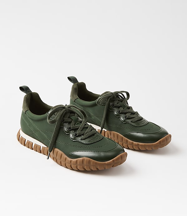A pair of green sneakers with brown soles rests on a white background.