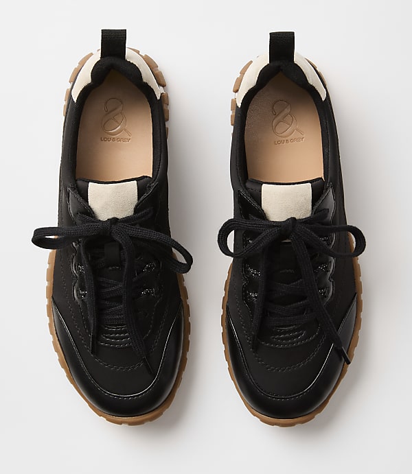 A pair of black sneakers with tan soles and laces rests on a plain white background.
