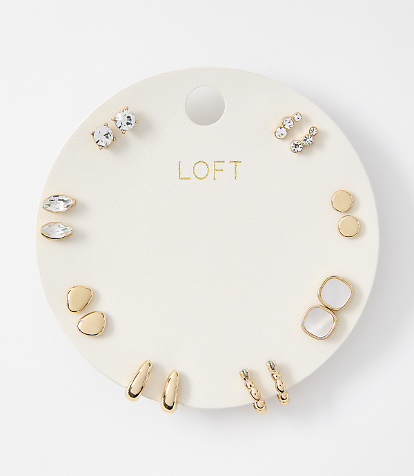 A collection of assorted gold and crystal earrings are displayed on a white circular card against a plain white background.