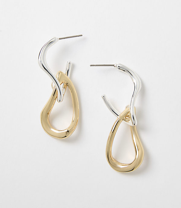 A pair of two-toned earrings with a silver hoop and a gold teardrop pendant hang against a plain white background.