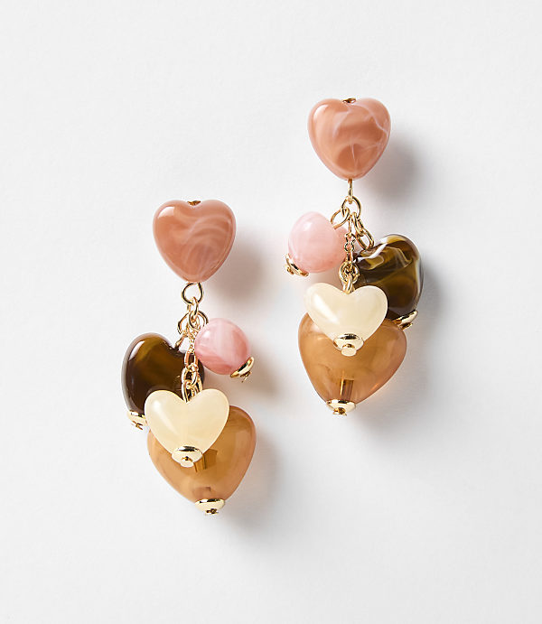 A pair of dangling heart-shaped earrings with various shades of pink, brown, and cream beads are displayed against a plain white background.