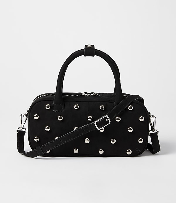 A black studded duffel bag with a crossbody strap rests on a plain white background.