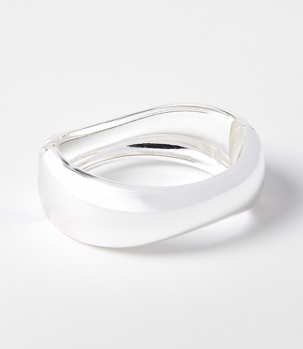 A sleek, silver, wavy bracelet rests on a clean white background.