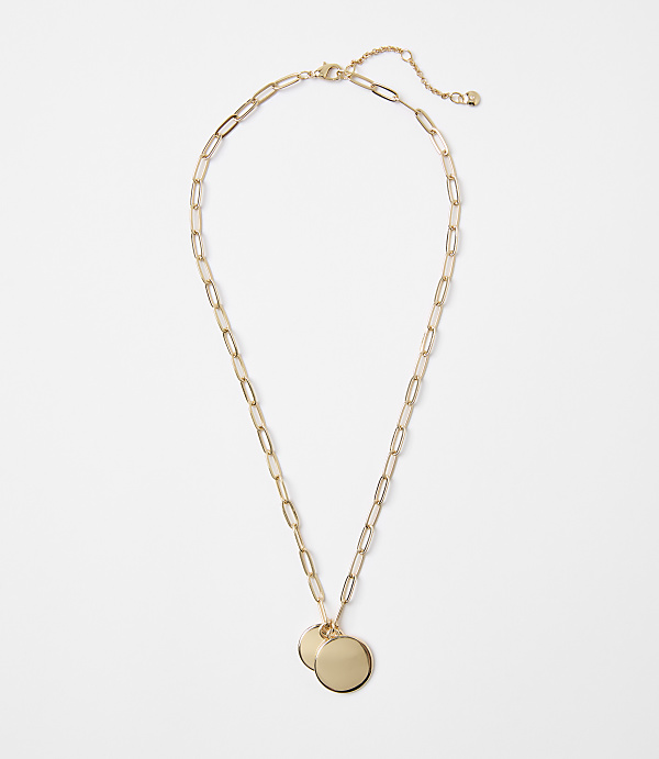 A gold necklace with two circular pendants rests on a plain white background.